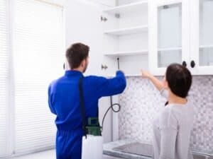 disinfestatore in divisa blu in cucina durante un trattamento per eliminare la blatta del legno